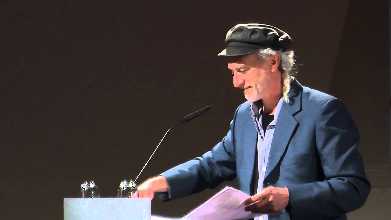 Ein Mann auf einer Bühne hinter einem Pult hält eine Rede.