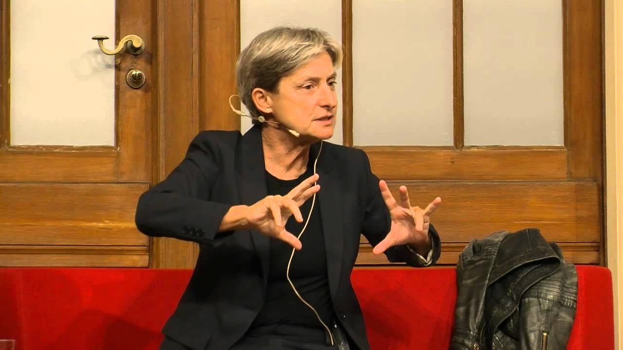 Judith Butler sitzt auf einem roten Sofa