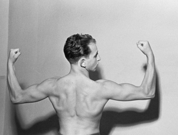 Portrait of a boxer (Possibly Neumann or Erich Seelig). Shot from behind, he presents his upper body muscles. Head slightly bent backwards.