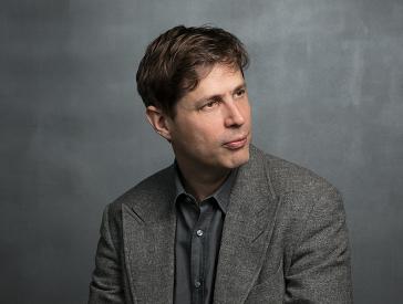 Porträtaufnahme: ein brünetter Mann (Daniel Kehlmann) im Halbprofil nach rechts schauend.
