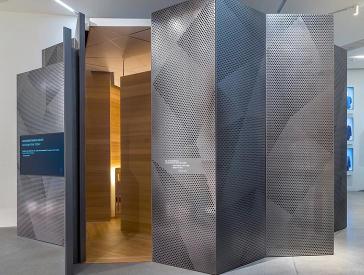 The debate room in the exhibition was realized as an eye-catching, jagged space within a space; its exterior is clad with perforated panels of metal, its interior with inviting-looking wood