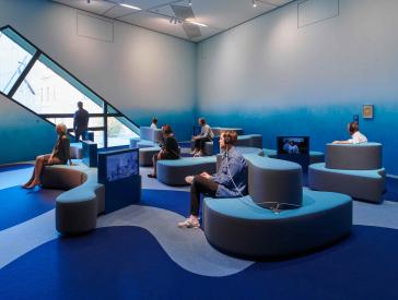 Room in shades of blue with wave-shaped seating and recessed TV screens