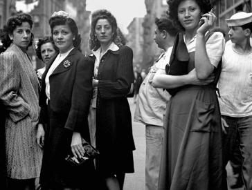 Black and white photo, a group of women standing on a street and looking into the camera.