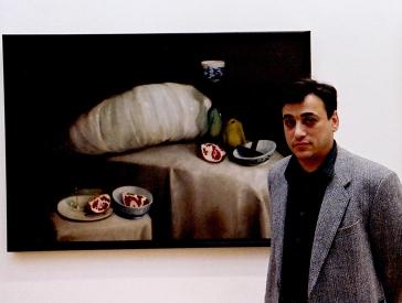 A young man stands in front of a still life depicting sliced pomegranates