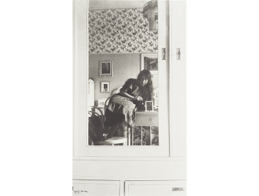 Teenage girl in a mirror attached to the door of a light cabinet