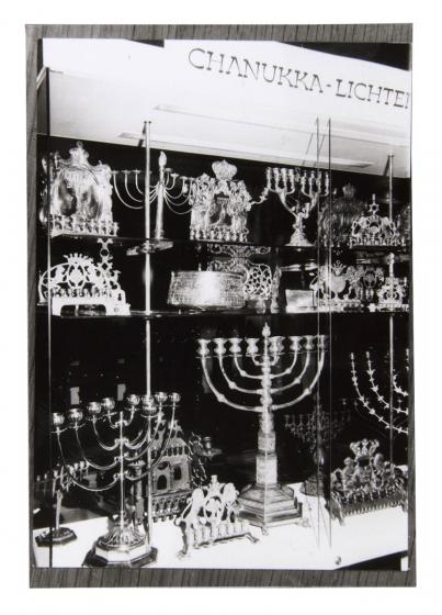 Black and white photo of a display case with many Hanukkah menorahs