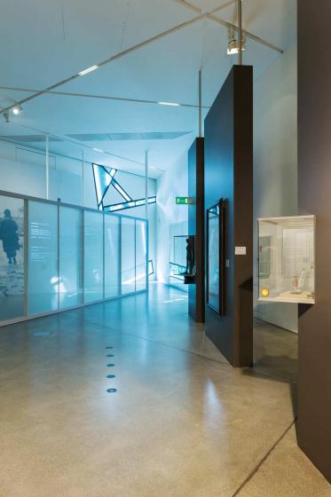 Ausstellungsraum mit auffällig blauer Lichtstimmung, im Hintergrund die Dreyblatt-Installation, rechts Vitrinen