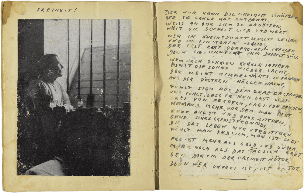 Handwritten two-page spread in print letters with a pasted photo of a man looking through the bars of his prison cell, bearing the title “Freiheit” (Freedom).