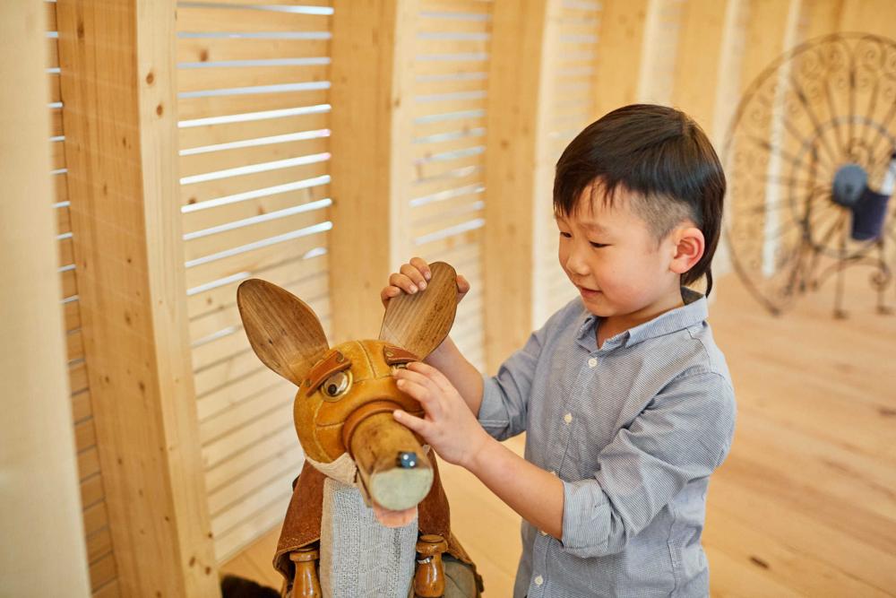 Kind berührt einen aus einem Volleyball und Holzelementen gebauten Fuchs