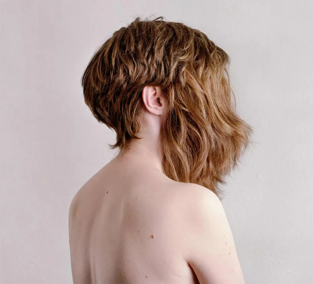 Fotografie einer Frau, die zwei Perücken trägt, eine davon bedeckt ihr Gesicht