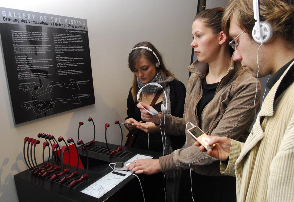 Three visitors with headphones and output station with headphones