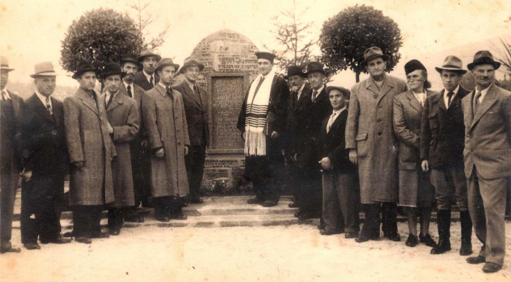 People in hats, nearly all of them men, standing in rows around a stone memorial 
