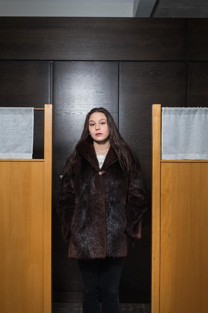 Photo: a woman in a fur coat in front of a dark veneer panel