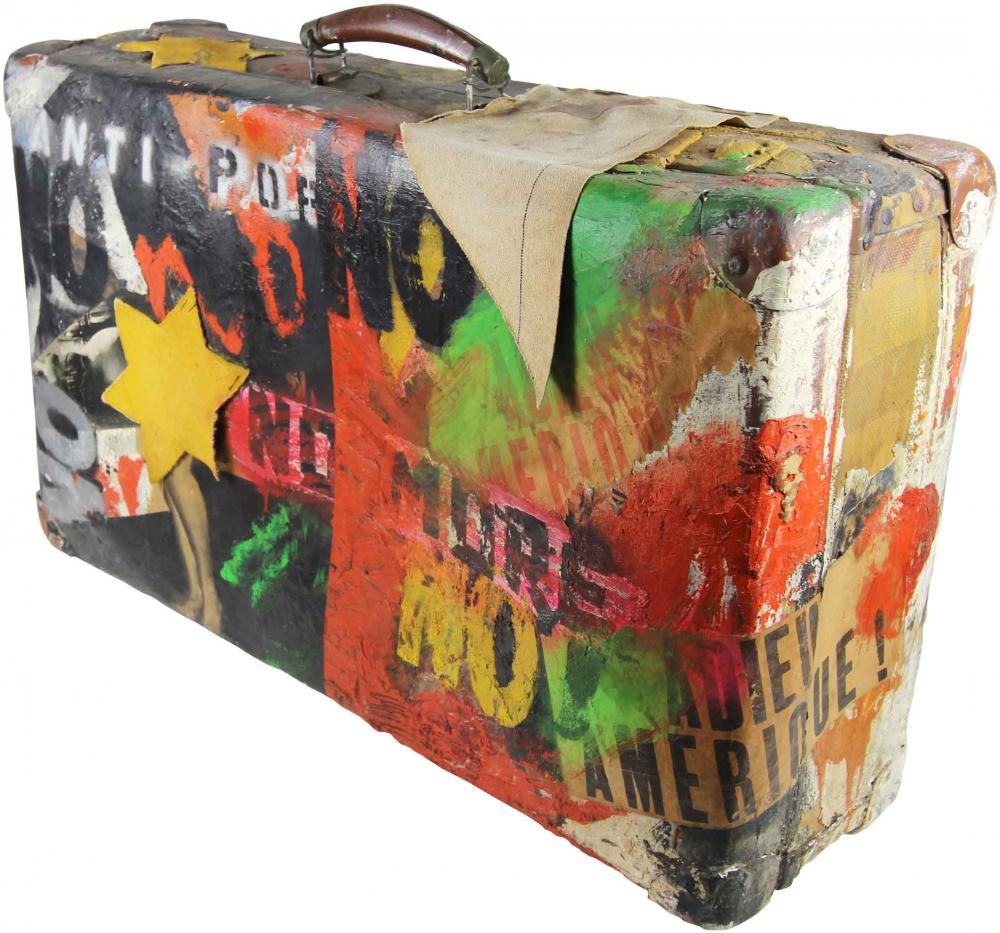 A suitcase, spray-painted and covered in stickers, with the Star of David and inscriptions like “NO”, “Adieu Amerique!”, “Anti-Pop”