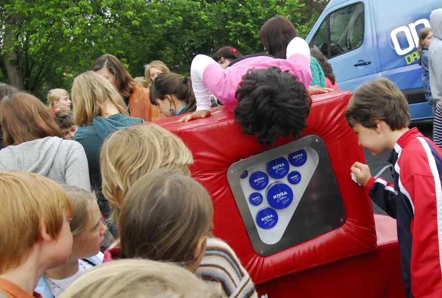 Kinder sind um und auf den mobilen Ausstellungswürfeln versammelt. Darin entdecken sie unterschiedlich große Nivea-Dosen.