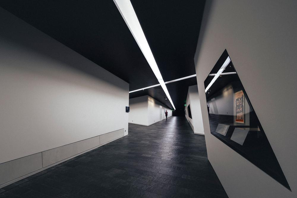 A long corridor with white walls, black floor and showcases in the walls.