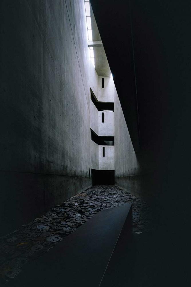 Narrow concrete hall, on the floor metal plates in the shape of a human head.
