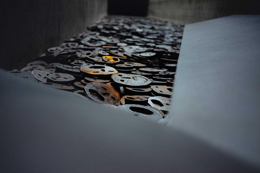Metal plates in the shape of human faces lie stacked on top of each other.
