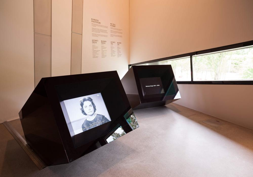 Two television screens are encased in black, reflective boxes and extend at an angle towards the viewer