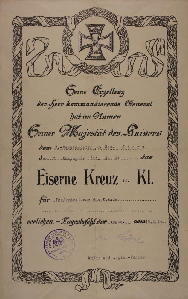 Urkunde, umrahmt mit Lorbeermotiv, oben zentral Darstellung eines Eisernen Kreuzes mit Jahreszahl 1914 und Krone