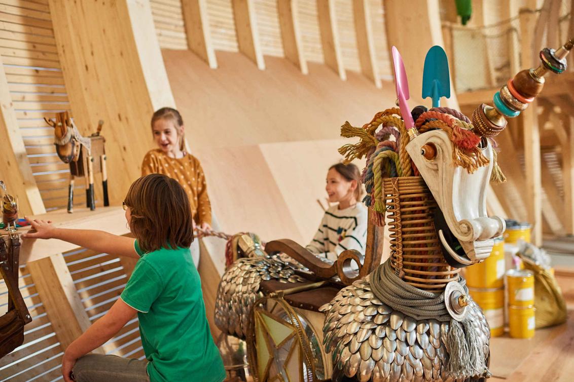 A unicorn made of spoons, shovels and other elements behind which children play