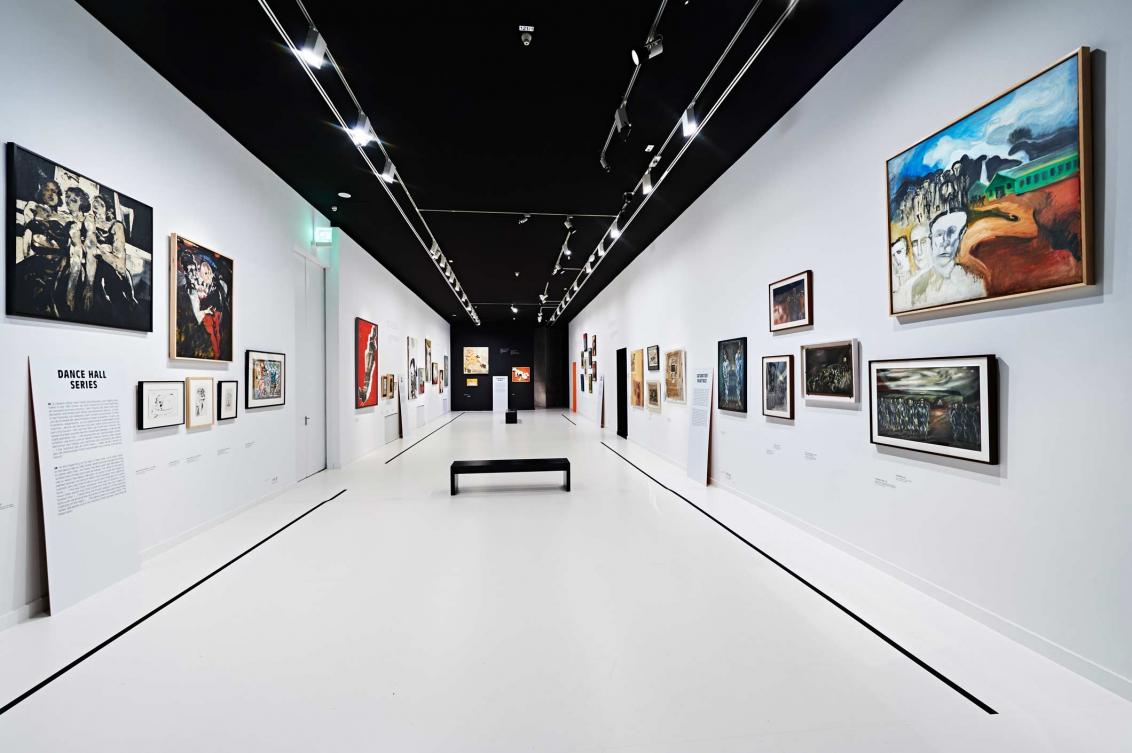 Gallery space, the white walls are filled with colorful paintings