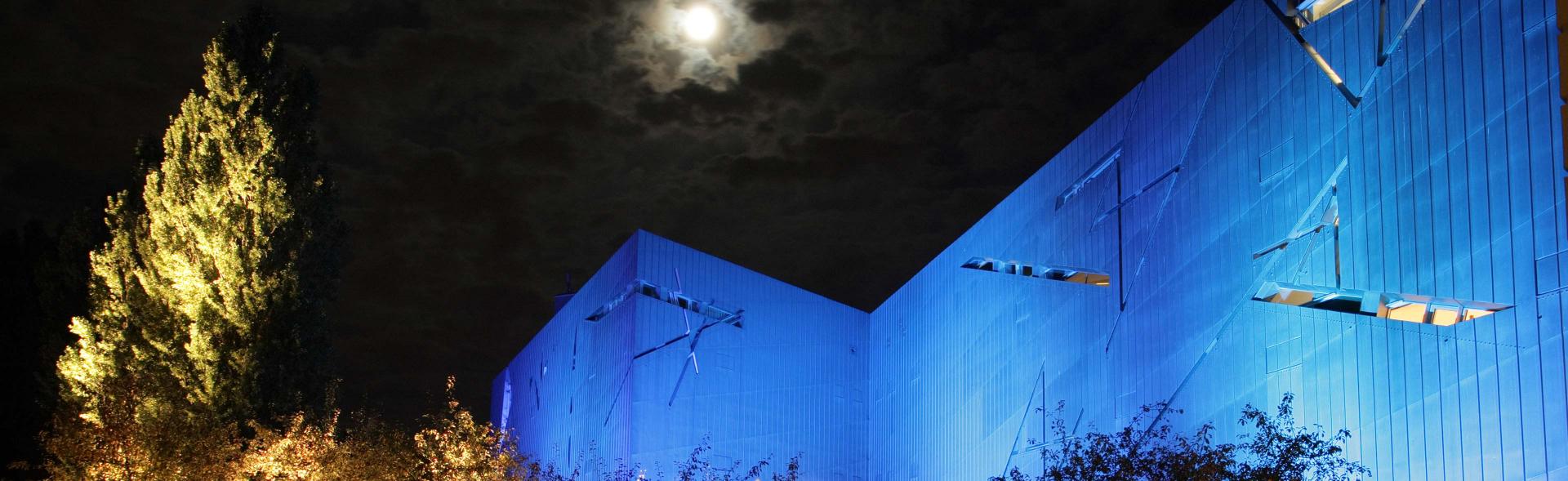 Libeskind-Bau blau angestrahlt, nachts, bei Vollmond