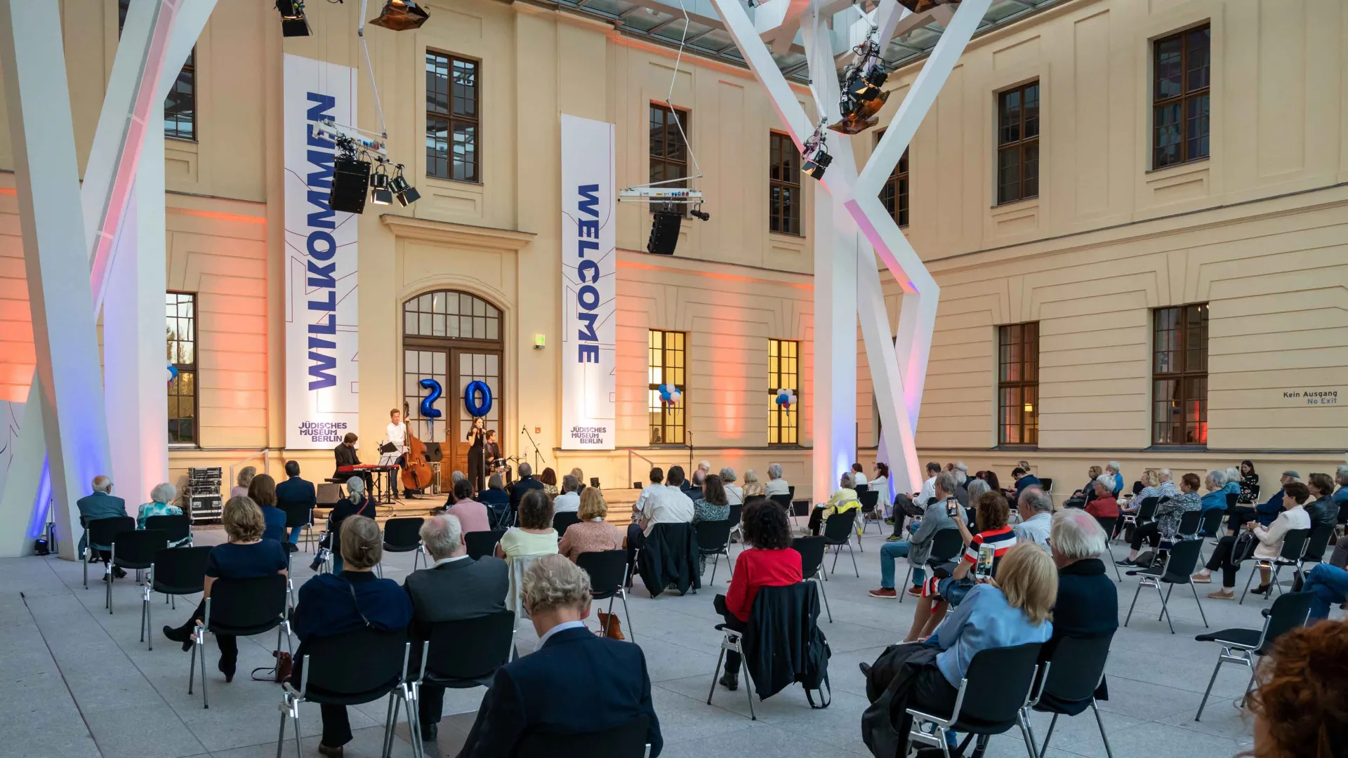 The glass courtyard of the JMB, a band on stage, the audience seated on chairs spaced apart.