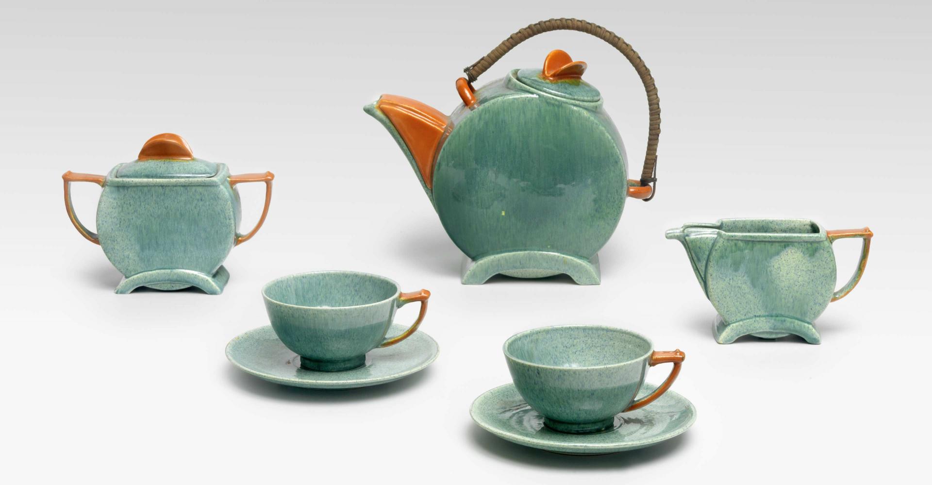Photo of a green-orange tea set, art deco, with a pot, two cups with saucers, sugar bowl and milk jug by Kadar Ltd.