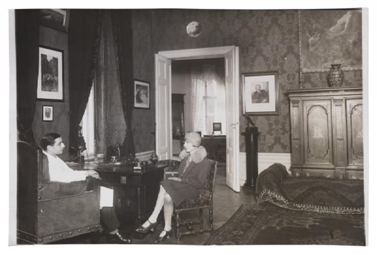 Schwarz-Weiß-Fotografie einer Frau und eines Mannes, die sich in Sesseln gegenüber sitzen
