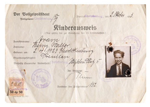 Ausweisformular in Frakturschrift, handschriftlich ausgefüllt. Im dafür vorgesehenen Feld ist das Passfoto eines Kindes aufgeklebt, das in den Ecken gelocht und mit Stempeln versehen ist.