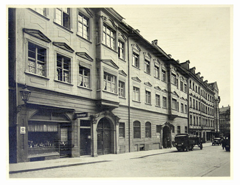 Black-and-white photograph of a large two-story building with display windows and wide entrances