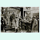 Members of the SA standing in front of a shop window with a bucket, brush and leaflets. Passers-by are looking on with expressions ranging from interested to gleeful.