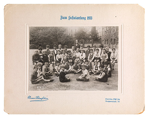 Class photo of thirty-six boys and their teacher, taken in the schoolyard.