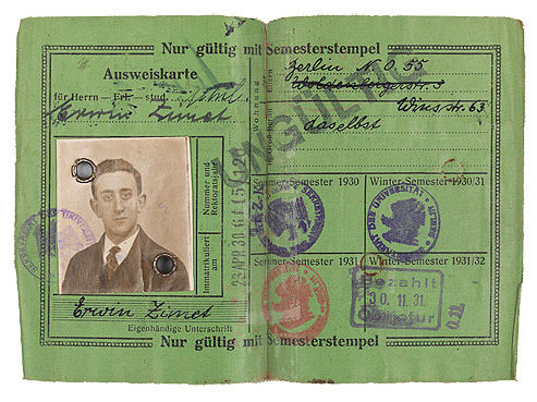 Green identification card filled out by hand with a passport photo and stamps from the university office.