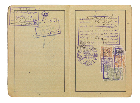 Open passport with handwritten entries and adhesive and ink stamps.