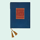 A book bound in blue and red leather with a gold embossed cover and a gold-colored tassel.