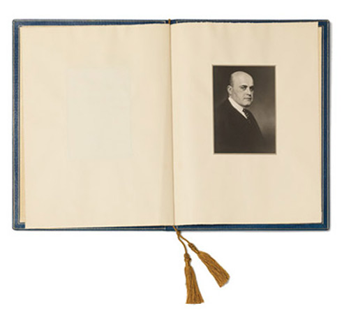 Open book, on the right a portrait photograph of a man in a dark suit and tie.