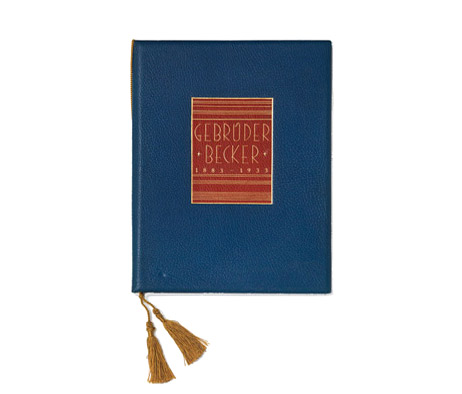 A book bound in blue and red leather with a gold embossed cover and a gold-colored tassel.