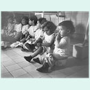 Eight small children sitting in a row on potties.