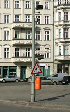 Construction site sign over a garbage can; buildings are visible in the background