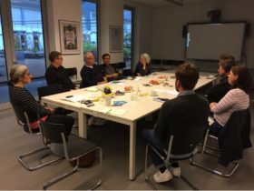 Nine people sit around a table