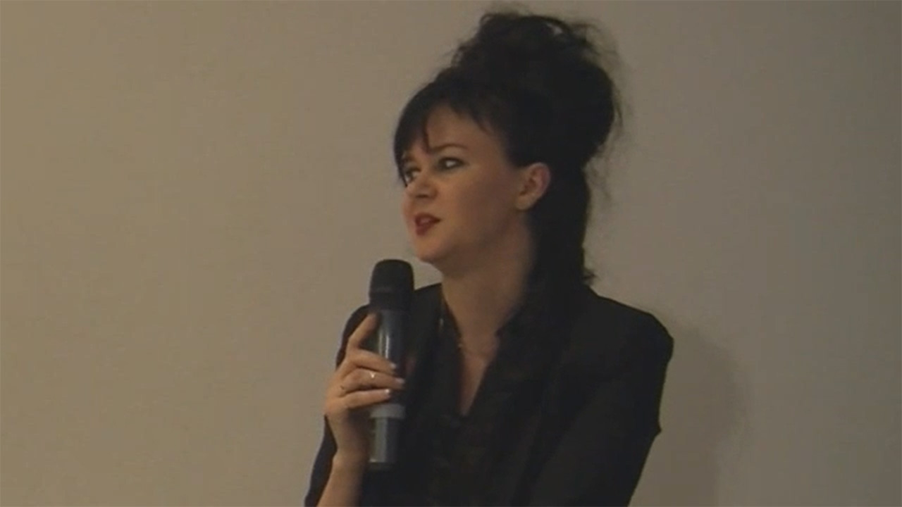 Woman speaking with microphone in hand.