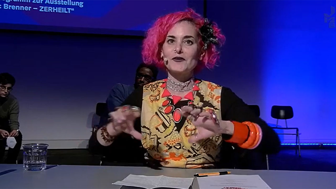 Woman gesturing with hands at a table.