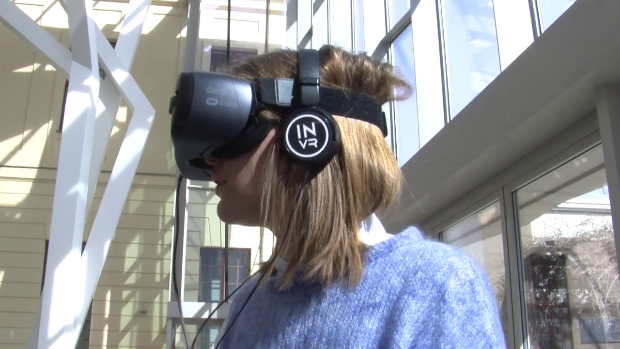 A woman wearing VR glasses stands in the glass courtyard of the Jewish Museum.