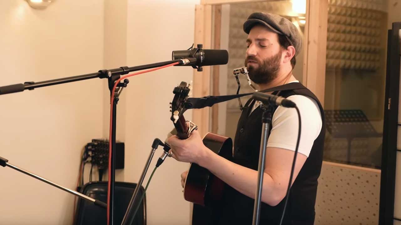 Daniel Kahn mit Gitarre in einem Tonstudio.