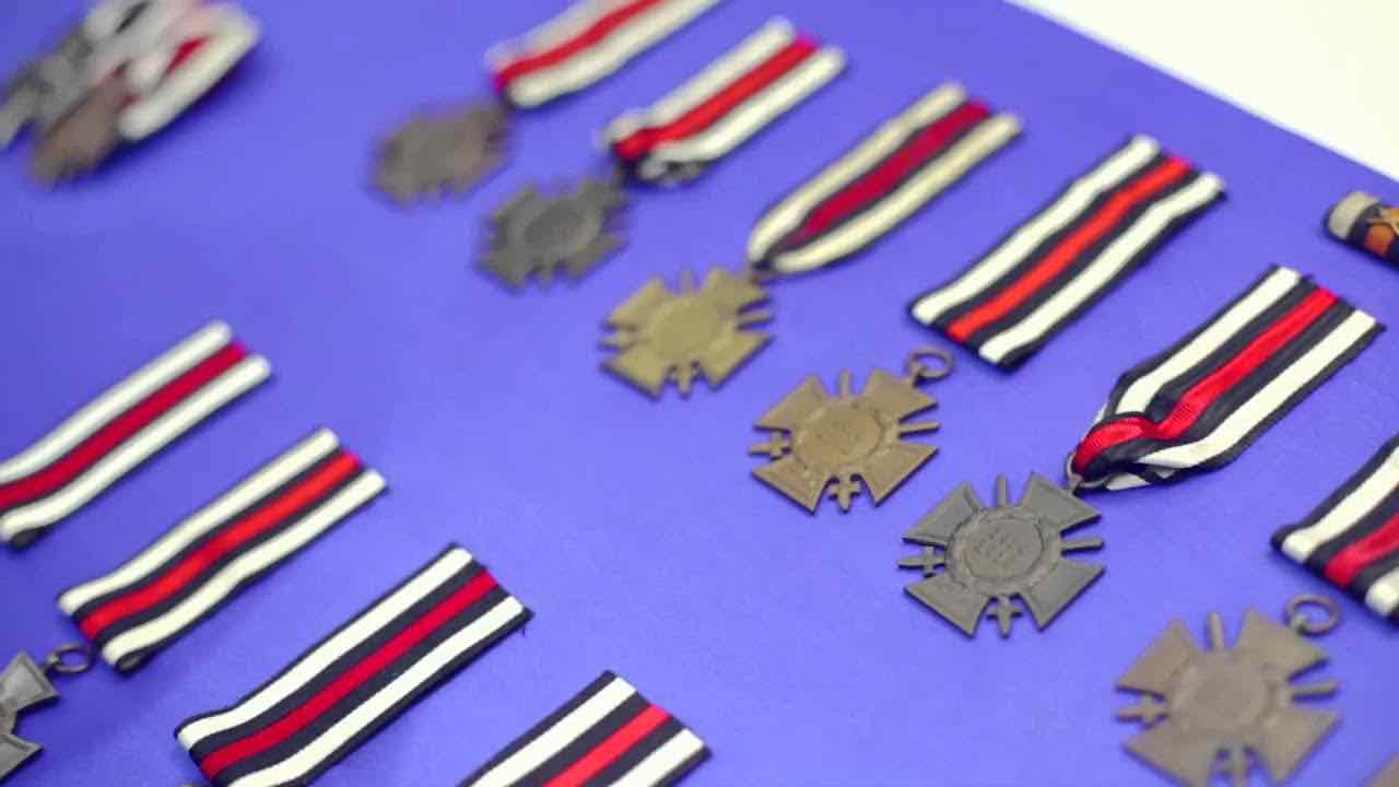 Iron crosses with ribbon buckles lie strung on a purple background.