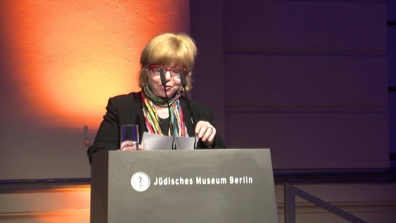 Woman standing at a lectern giving a lecture.