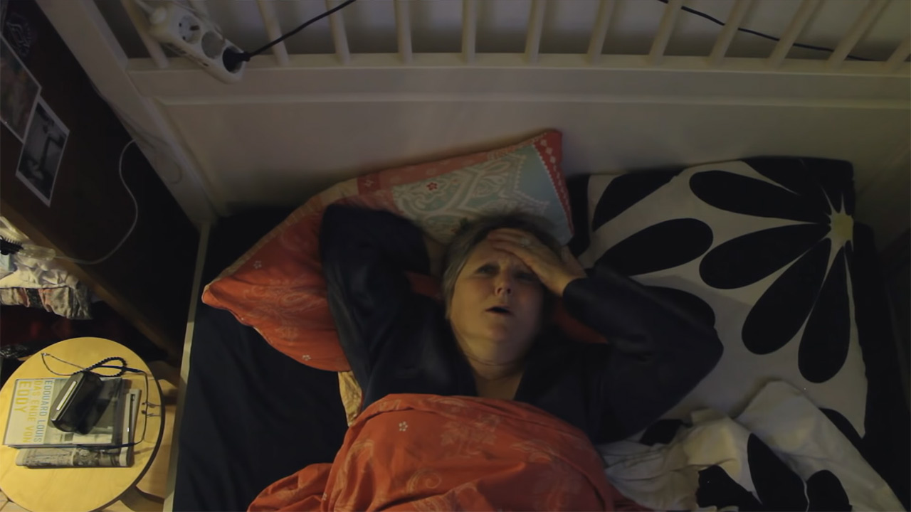 Woman lying in bed and holding her forehead with her hand.