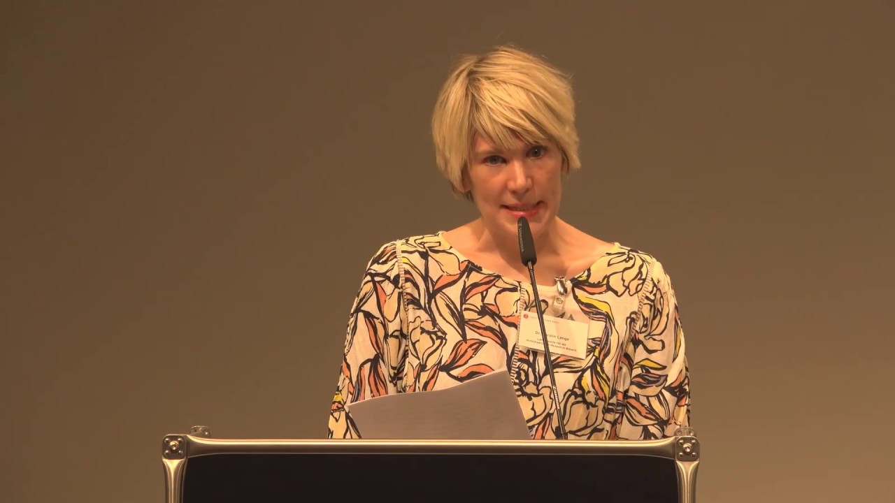 Woman at lectern gives a lecture.